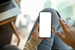 Close-up image of a woman in jeans relaxes sitting in the cafe and using her smartphone. smartphone white screen mockup for display your graphic banner.