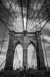 Vertical view from below of Brooklyn Bridge - a hybrid cable-stayed suspension bridge in New York City, spanning the East River between the boroughs of Manhattan and Brooklyn. Black and white photo.