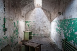 The Eastern State Penitentiary a former American prison in Philadelphia, Pennsylvania. The view of an abandoned  decaying cell with furniture and a single glass skylight, representing the 