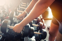 Sport girl holding weight on blurred background of Gym fitness