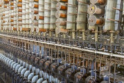 Wooden spools and bobbins on machinery in turn of the century silk throwing factory.