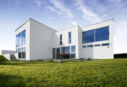 Modern Norwegian design house in concrete white with large windows and green lawn
