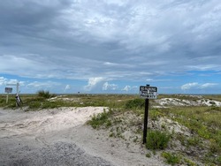A no parking private property sign at a beach in Rosemary Beach, Florida on a cloudy day.