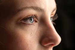 closeup photo of a young woman crying with a tear running down her cheek.