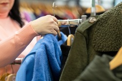 shopping. woman shopper choosing outerwear in the mall. female hands holding hanger with coat. closeup