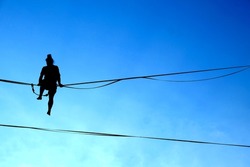Lublin, Poland 29 July 2022. Silhouette of a young man sitting on a tightrope at Urban Highline Festival