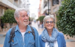 Happy smiling senior couple of tourist walking in the city. Attractive white haired caucasian people enjoying freedom travel vacation