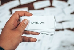 Flash Card with the Word Ambitious  Held Against Background of scattered Flash Cards