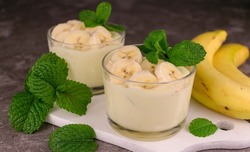 Banana mousse in low glasses with mint on a white board. Close-up.

