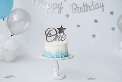 Festive background decoration for birthday celebration with gourmet cake and blue balloons in studio, cake smash first year concept