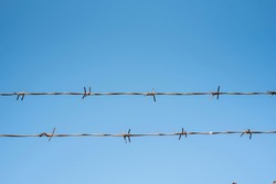 Barbed wire fence over blue sky