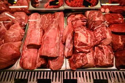 various raw meat in showcase of butcher shop. Bloody Meat Chops.