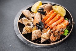 seafood plate assorted shrimps, crab claws, clams, rapan, trumpeter mollusk Takeaway healthy meal food snack on the table copy space food background rustic top view