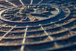 Close-up of the metal manhole cover in the sunshine.