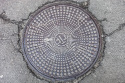 Manhole with metal cover in cracked asphalt surface