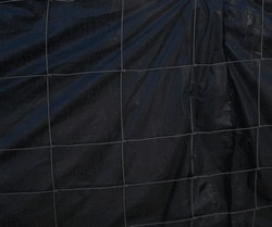 Metal wire fence and black synthetic fabric. 
