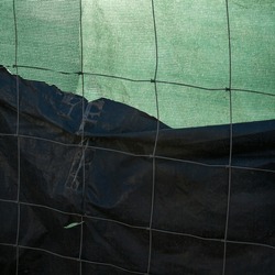 Metal wire fence and green and black synthetic fabric. 