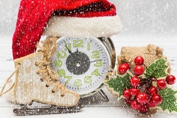 New Year or Christmas card - alarm clock in Santa Claus hat, ice skates and holly. Christmas and New Year concept.