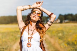 Pretty amazing free red-haired hippie girl dancing outdoors, feathers and braids in her hair, white dress, vest with fringe, accessories, sunglasses, tattoo flash, indie, Bohemian, bo-ho style