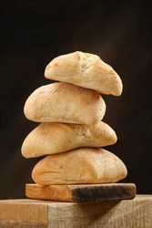 Stack of a ciabatta bread or bun on a wooden board . Freshly baked traditional bread. Shallow depth of field