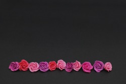 Raw Mix of pink and Peach Fake Plastic Mini rosess Flowers Black Background copy space. Craft, Art, Hobby concept.