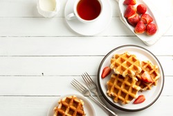 Delicious breakfast. Belgian waffles with honey and strawberries. Copy space, white wooden background