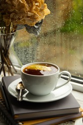 Tea cup on windowsil with rainy glass window.