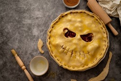 Cooking halloween apple pie, pumpkin face cutted in raw dough. Autumn baking concept, top view