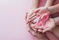 hands holding pink ribbons on pink background, Breast cancer awareness and October Pink day, world cancer day, national cancer survivor day