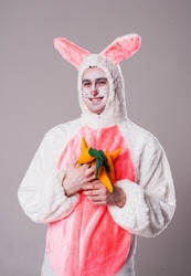 Young smiling man in bunny's costume carrying carrots 