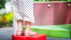 Selective focus. Child feet in a playground, Girls legs are climbing on playground equipment at outdoor playground. Active children have fun. Empty space to enter text.