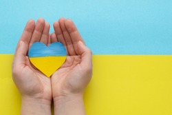 The concept of ending the war in Ukraine. heart in the colors of the flag of Ukraine in female hands