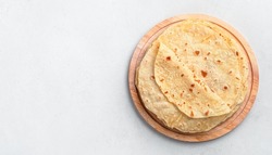 Indian chapati tortillas on a wooden board on a gray background. Traditional Indian food. Top view, copy space