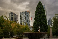 DOWNTOWN BELLEVUE WASHINGTON SKYLINE WITH A WATER FOUNTAIN AND A AMERICAN FLAG FROM THE DOWNTOWN CITY HALL PARK
