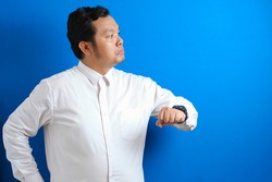 Asian businessman wearing white shirt check time on his wrist watch, tired annoyed gesture for waiting too long