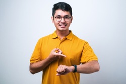 Young handsome man wearing casual shirt standing over isolated white background In hurry pointing to watch time, impatience, upset and angry for deadline delay