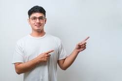Young handsome asian man wearing casual shirt over white background with a big smile on face, pointing with hand finger to the side looking at the camera.