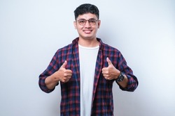 Young handsome man wearing casual shirt over white background approving doing positive gesture with hand, thumbs up smiling and happy for success. Winner gesture.