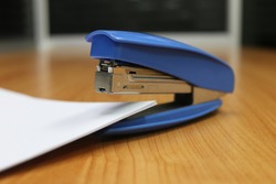 Photo of blue stapler put on the table in office, stapler is a device used in schools or offices 