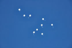 Nine white baloons floating in the blue  sky at the Sheikh Zayed Heritage Festival, UAE