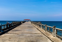 An empty local concrete pier with blue sky and Andaman sea as background