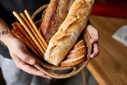 Close yp of man hand, holding basket with various bread freshly baked. Close up concept of homemade bread, small bakery, natural farm products, local food,  domestic production. Healthy and 