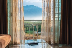 White curtain by the window and view of the mountain with light from the sunset, Beautiful curtain make the house more livable,The atmosphere of relaxation at living room in a holiday close to nature.