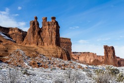 Three Gossips feature with snow on the ground and blue sky in Arches National Park