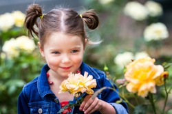 portrait of a young and adorable little girl in  a natural outdoor setting with out of focus roses