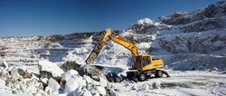 Quarry machine hydraulic breaker works in a winter stone quarry, panorama.