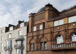 Red brick and white buildings with balconies and arched windows against a stormy sky