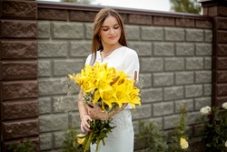 Girl with a bouquet of yellow lilies in her hands
