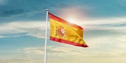 Spain national flag waving in beautiful clouds.