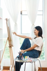 The art concept, Asian female artist using paint brush to painting for create artwork on canvas.